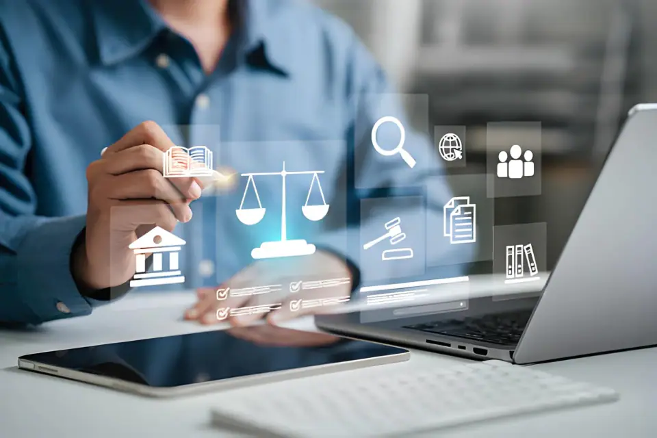 Professional at a laptop and tablet with holographic legal icons, including scales of justice, a gavel, a courthouse and document checklists