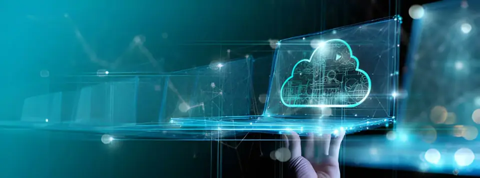 A hand holds a translucent laptop displaying a glowing cloud outline against a teal digital background